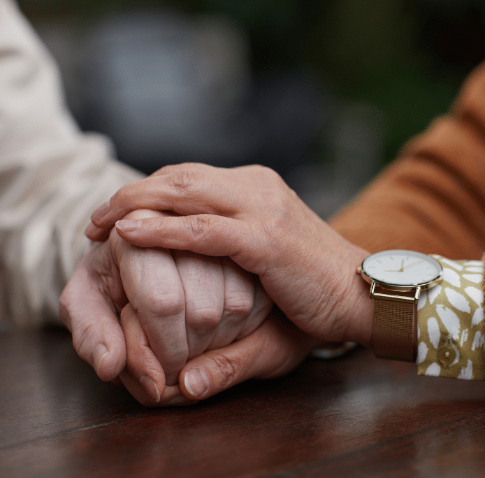 Eine Patientin und eine Mitarbeiterin formen gemeinsam ein Herz mit ihren Händen – Symbol für Fürsorge und Vertrauen bei GBK-Krankenfahrten.